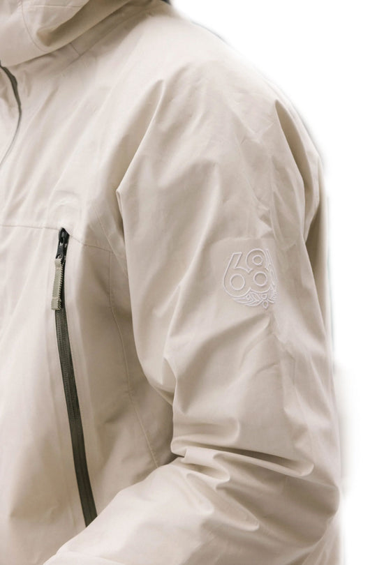 Close-up of a beige jacket with a brand logo on the sleeve against a white background