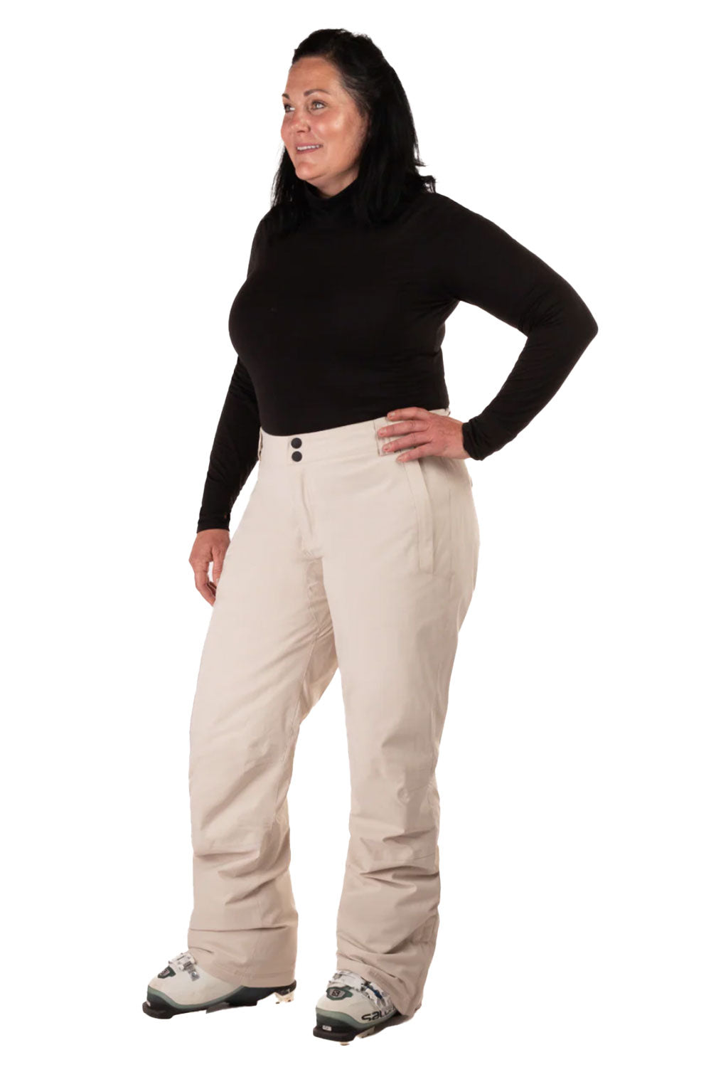Woman wearing beige snow pants and a black top on a white background