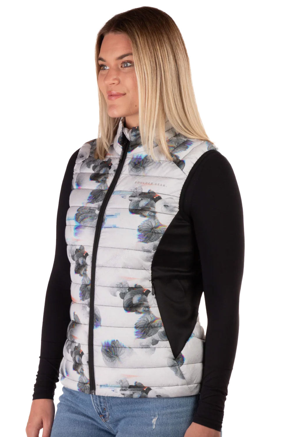 Woman wearing a patterned vest over a black long-sleeve shirt on a white background