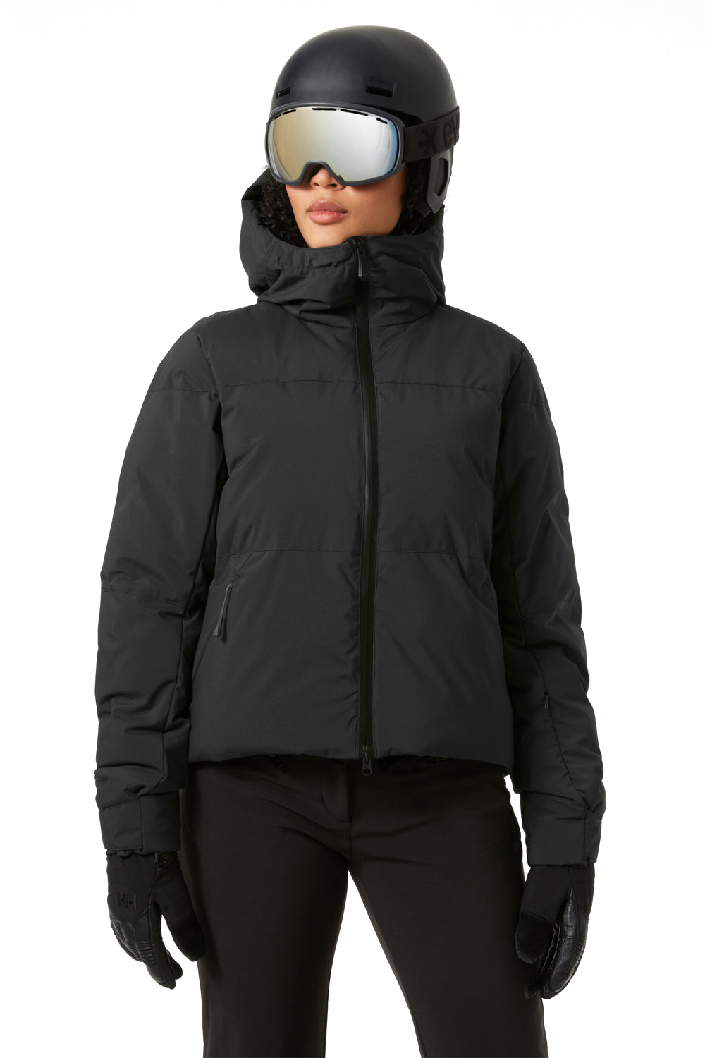 Person wearing a black puffy ski jacket, helmet, goggles, and gloves on a white background