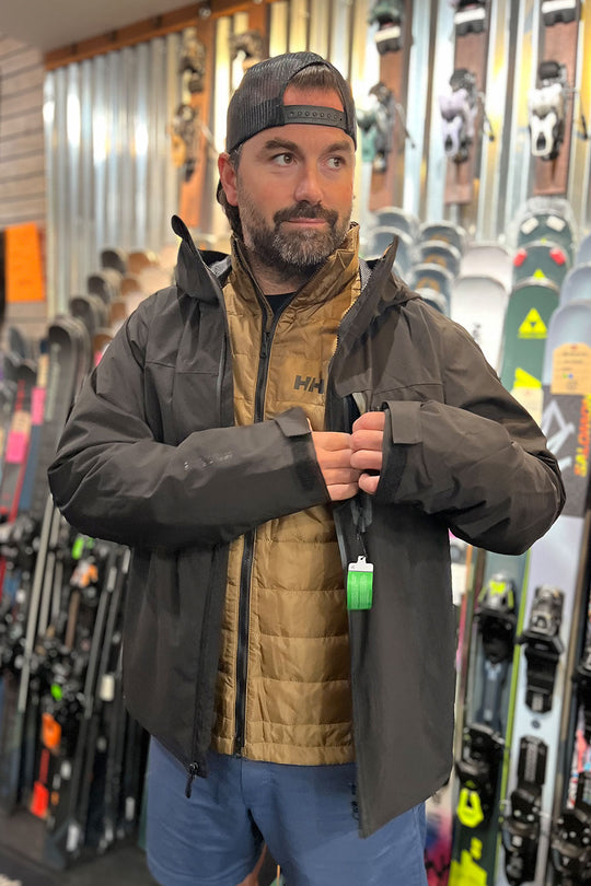 Man wearing a jacket with skis in the background