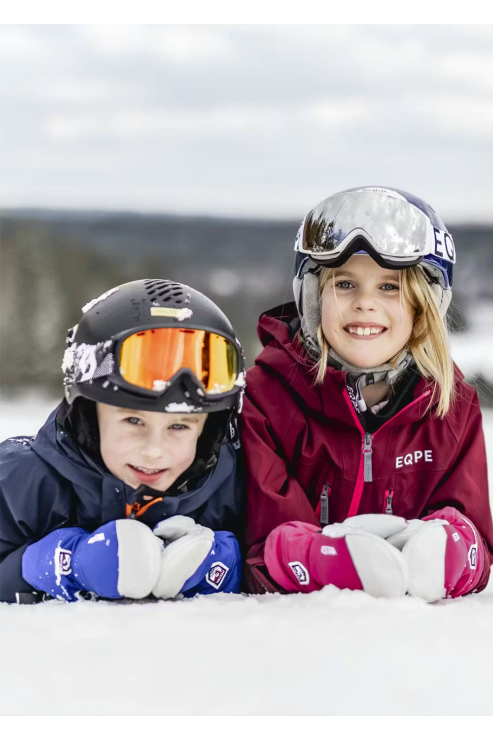 Two children in ski gear posing in the snow