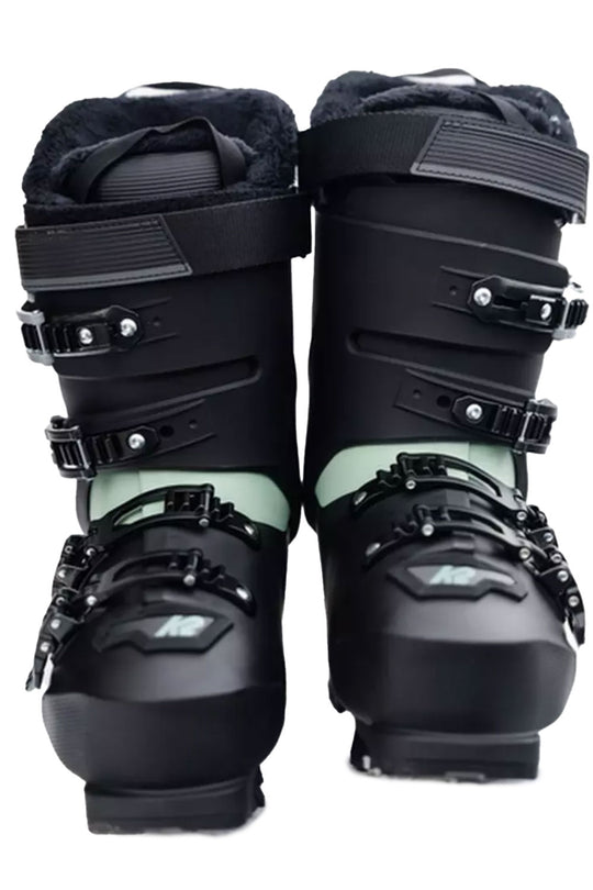 Pair of black ski boots with green accents on a white background