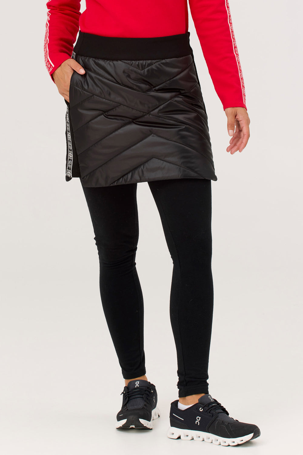 Person wearing a black puffer skirt, black leggings, and black sneakers on a white background