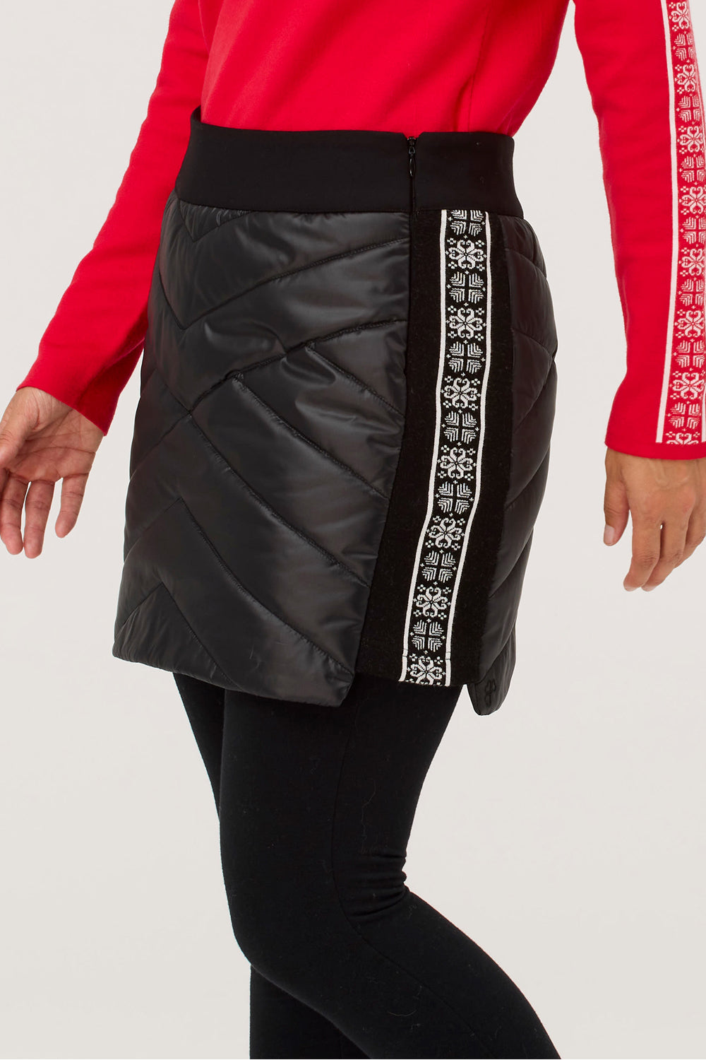 Black puffer skirt with white patterned side panels worn by a person in a red long-sleeve shirt.