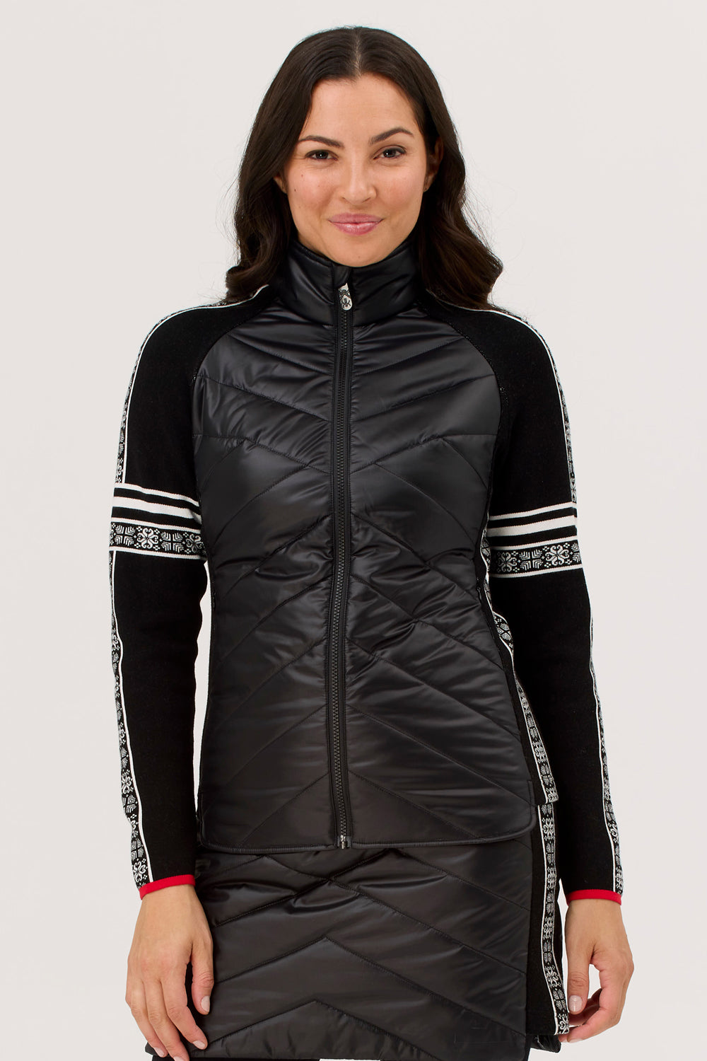 Woman wearing a black quilted jacket with white accents on a plain background