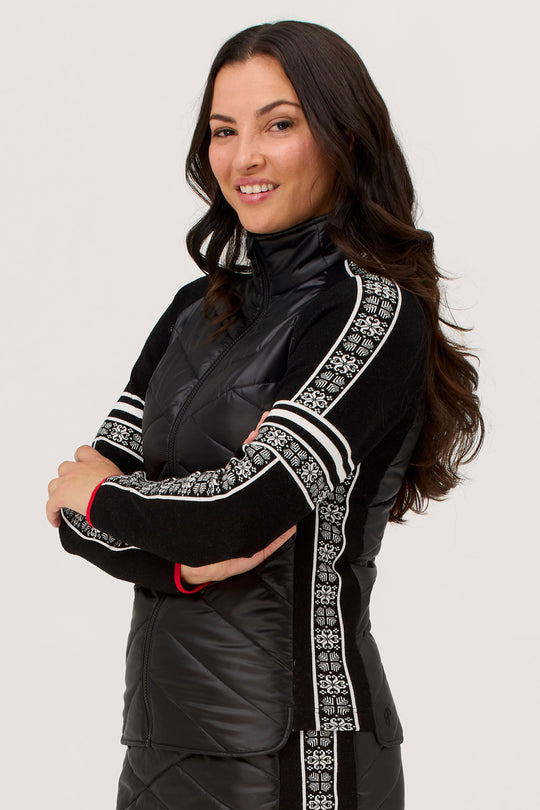 Woman wearing a black outfit with decorative white patterns on a plain background