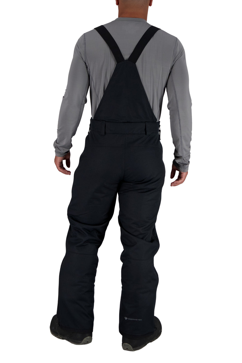 Person wearing black snow pants with suspenders on a white background