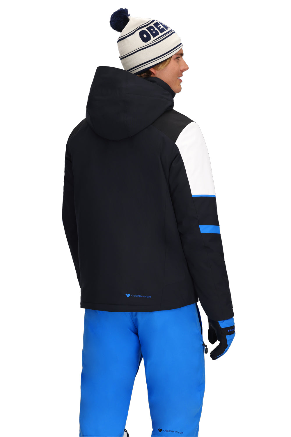 Person wearing a black, blue and white ski jacket with blue pants on a white background