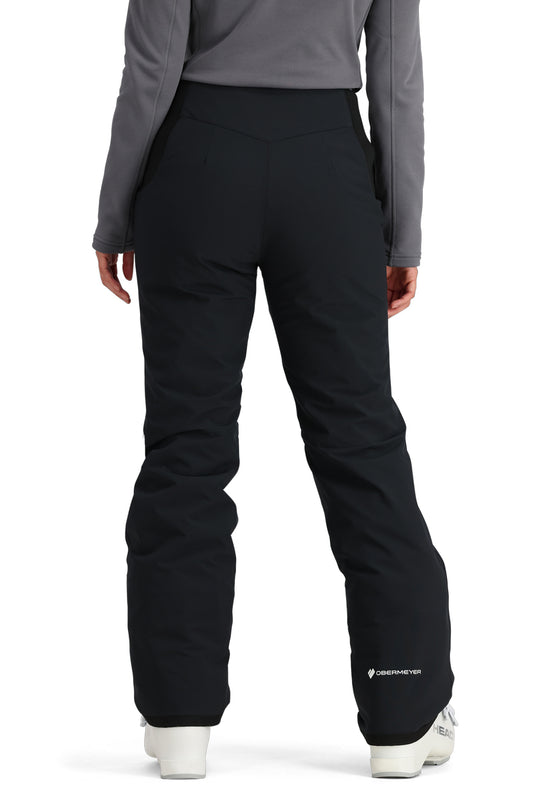 Person wearing black ski pants with a gray top on a white background