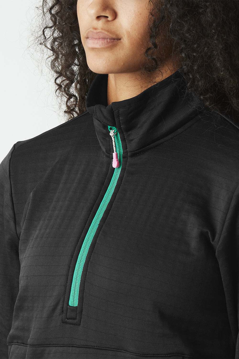 Person wearing a black quarter-zip sweatshirt with a green zipper detail.