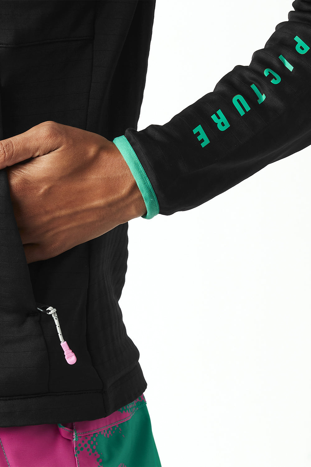 Close-up of a black jacket with green text on the sleeve, worn by a person.