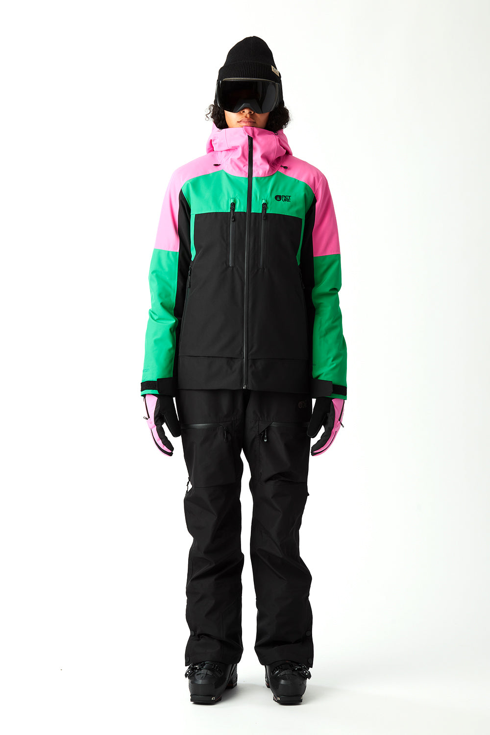 Person wearing a colorful ski jacket and black pants on a white background