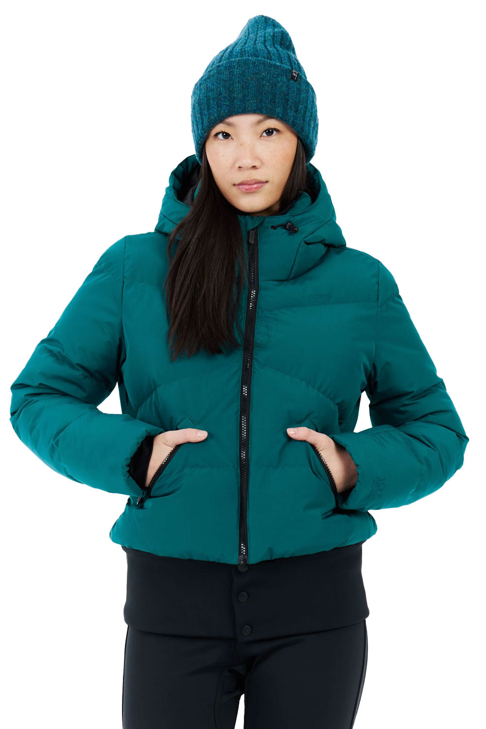 Person wearing a teal jacket and matching beanie on a white background