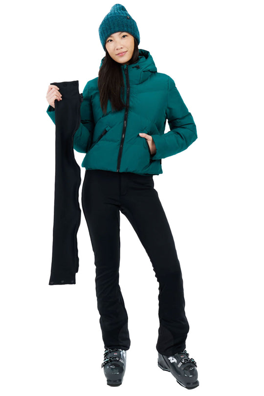 Person wearing a teal jacket and black pants holding a black ski pole on a white background