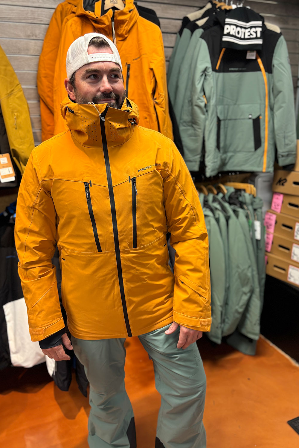 Person wearing a yellow jacket in a store with various jackets on display