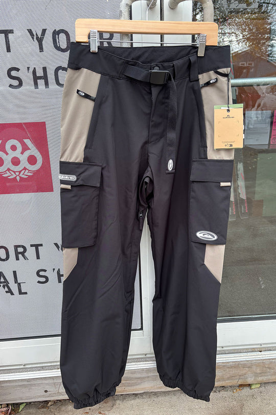 Black and beige pants on a hanger with a store window in the background