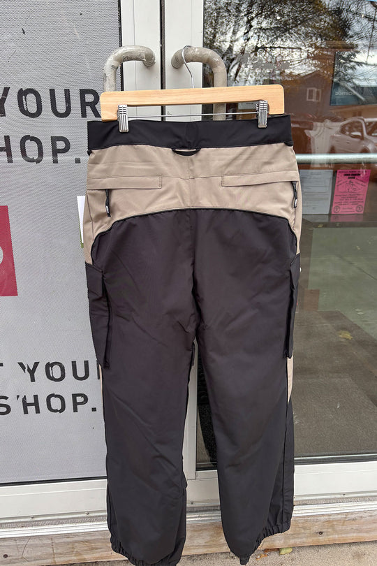 Black and beige pants on a hanger against a glass door background