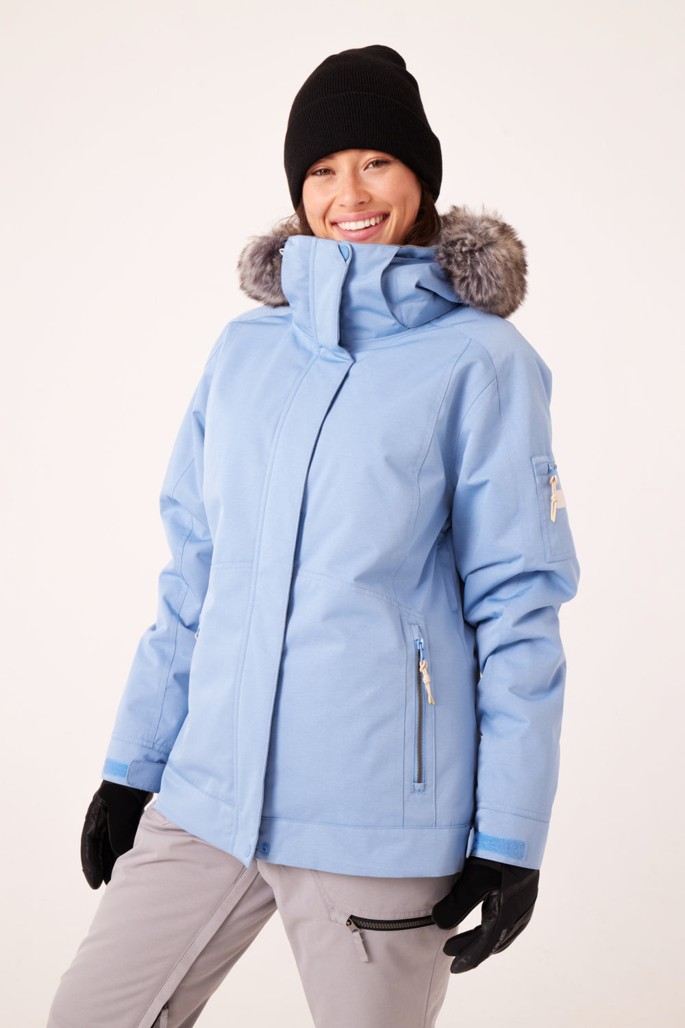Person wearing a light blue Roxy ski/snowboard jacket with faux fur hood on a white background