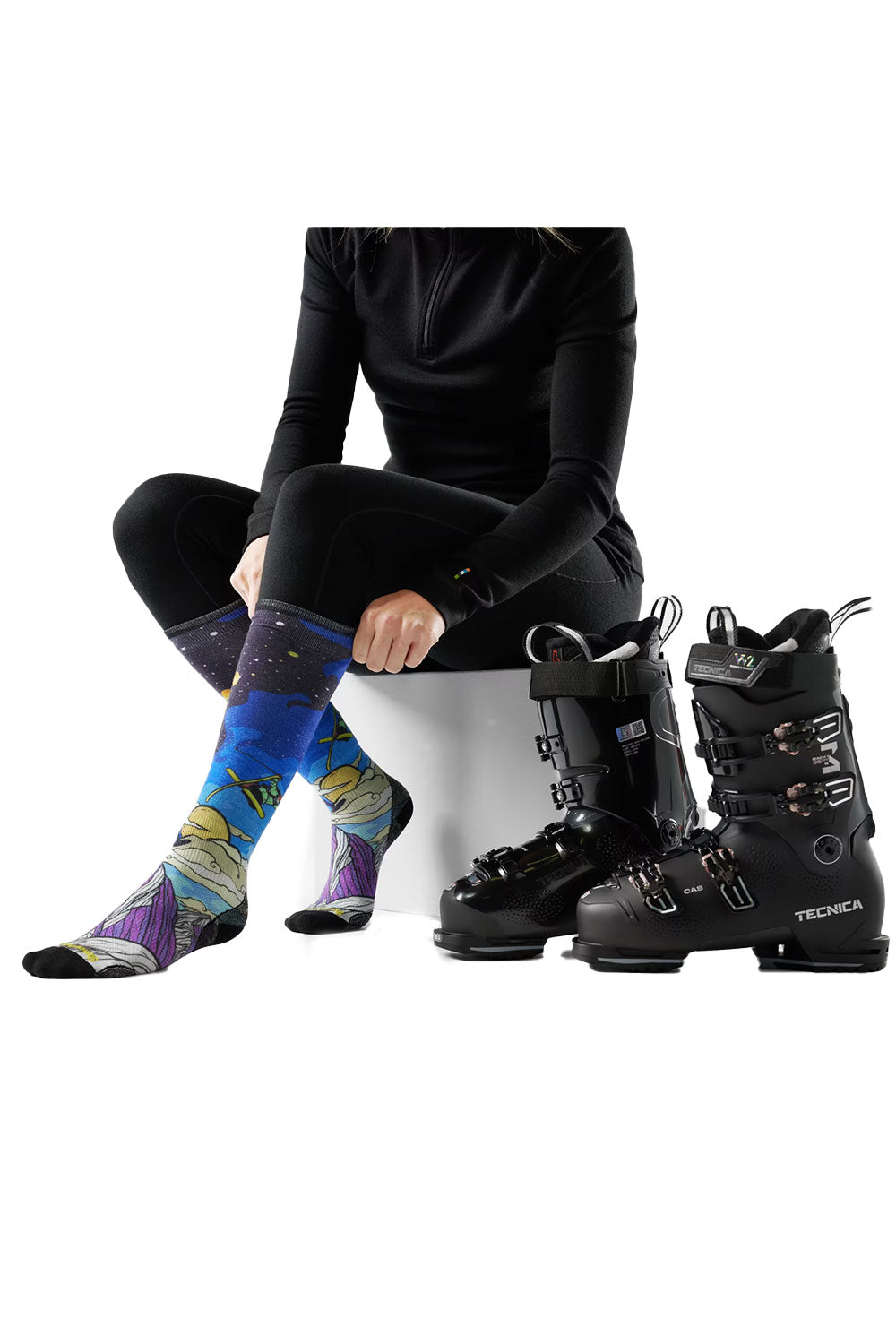 Person wearing colorful socks and black ski boots on a white background