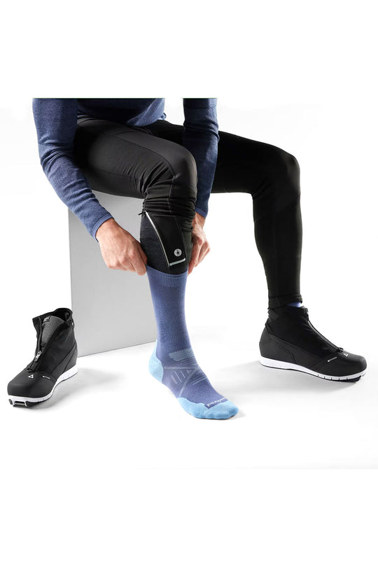 Person wearing black shoes, blue socks, and black leggings on a white background