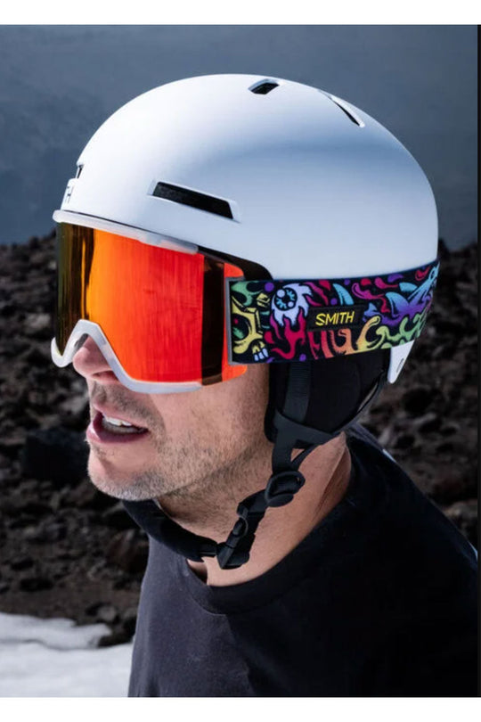 Person wearing a white helmet and colorful goggles with a dark background