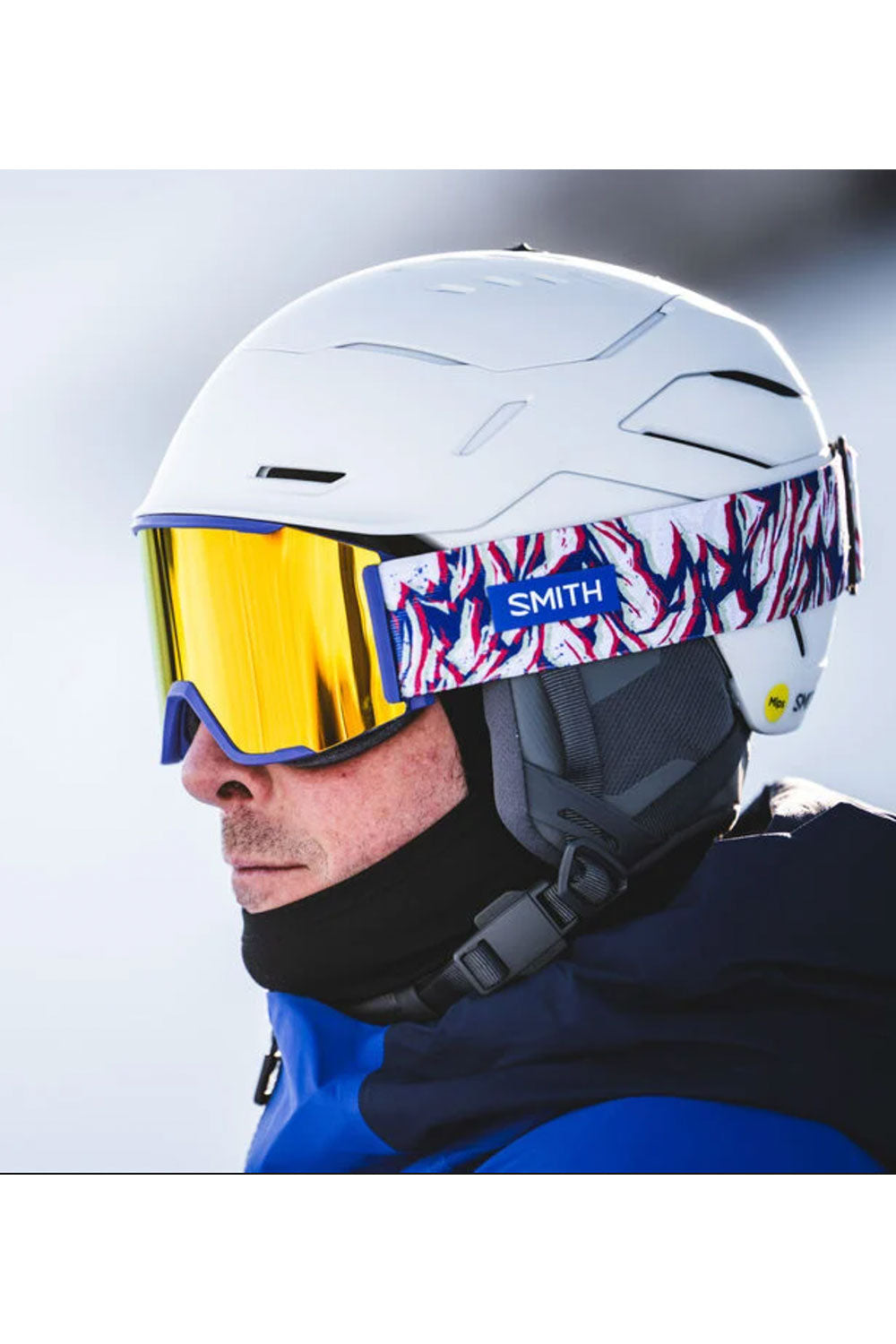 Person wearing a white helmet with colorful visor and blue jacket on a blurred background