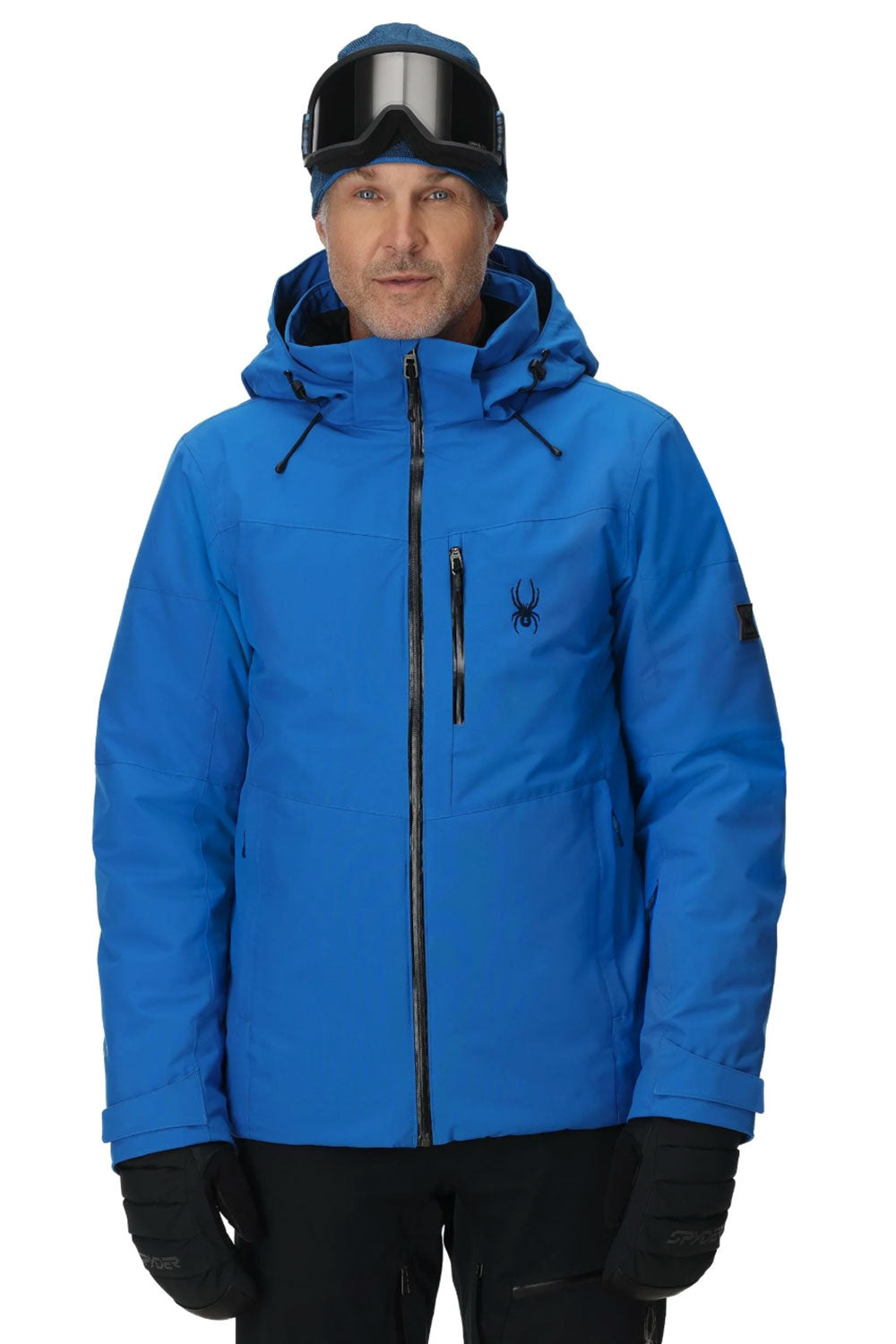 Man wearing a blue ski jacket with goggles on a white background