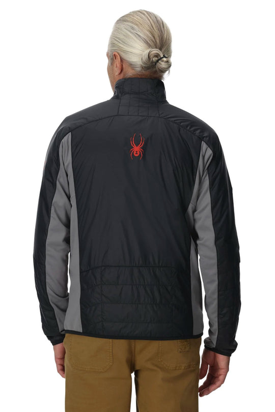 Person wearing a black and gray jacket with a red logo on the back, standing against a white background.