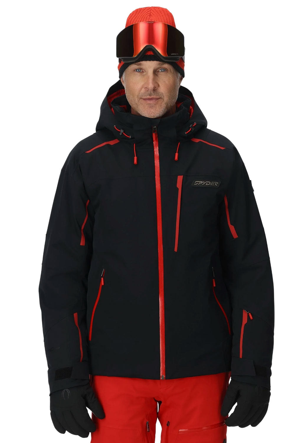 Person wearing a black and red ski jacket with goggles on a white background