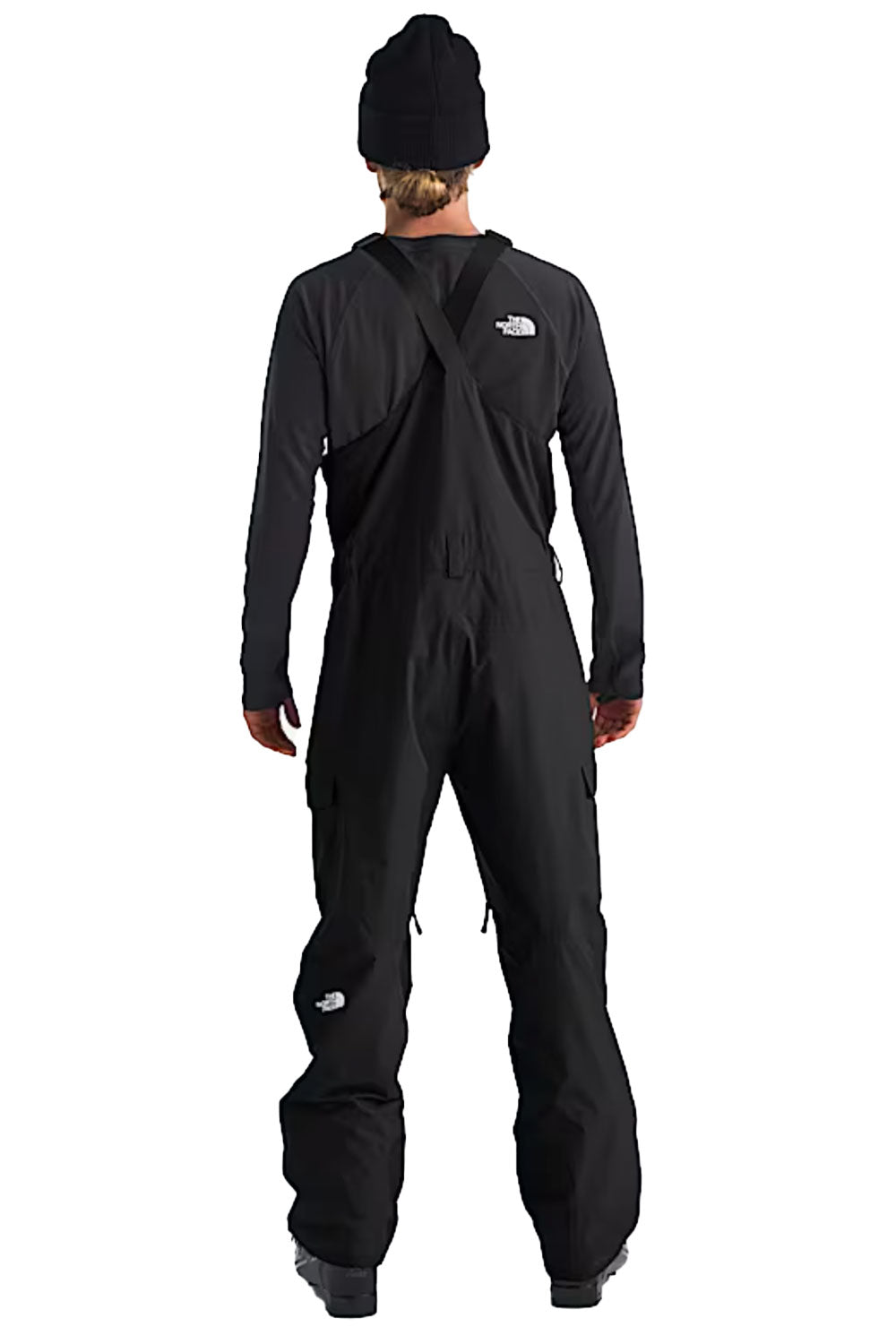 Person wearing a black ski bib with The North Face logo on a white background