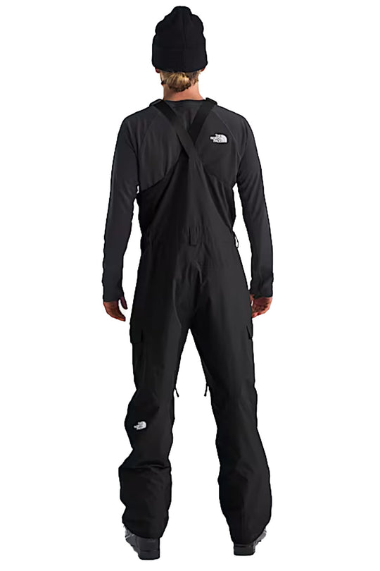 Person wearing a black ski bib with The North Face logo on a white background