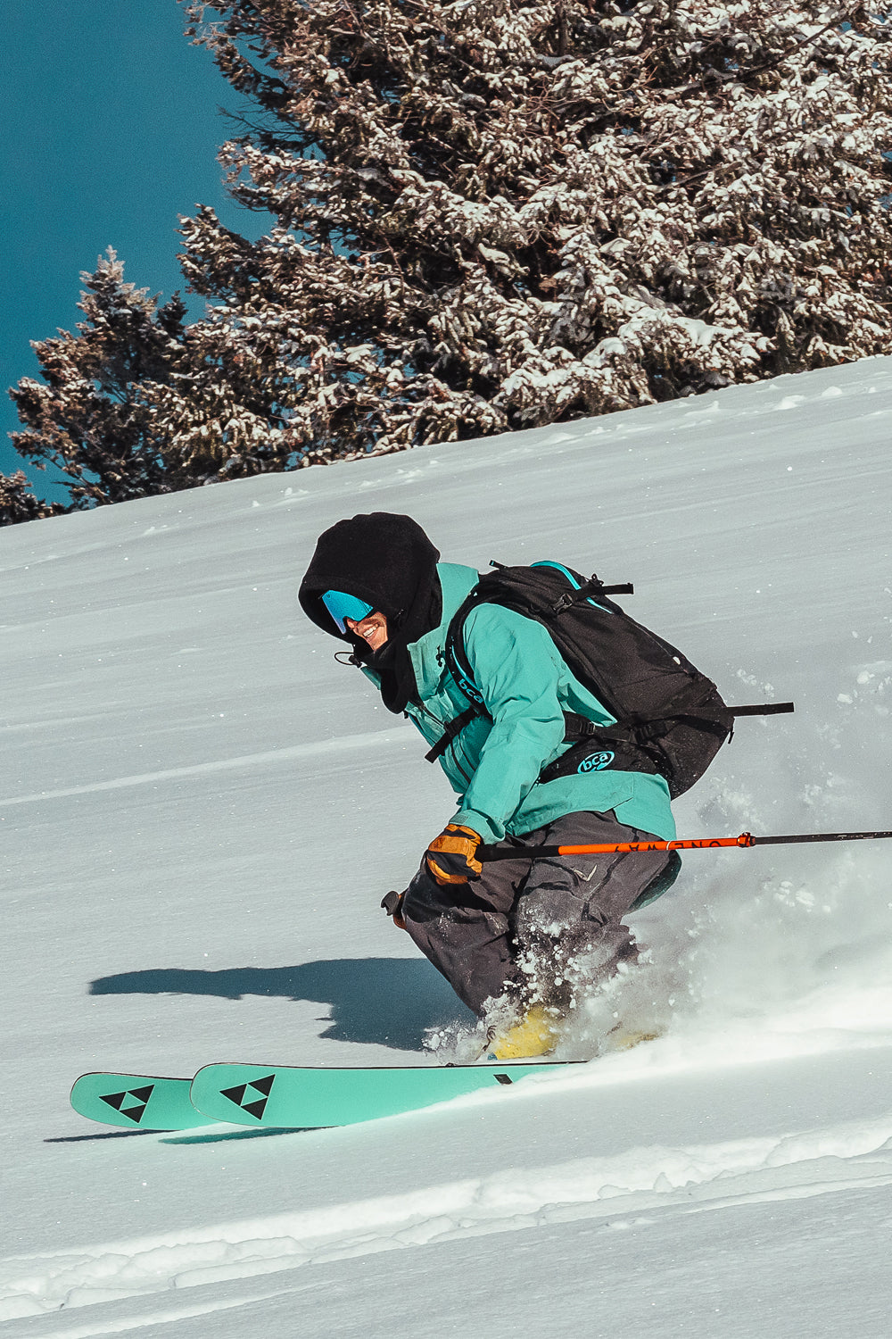 Person skiing down a snowy slope with trees in the background