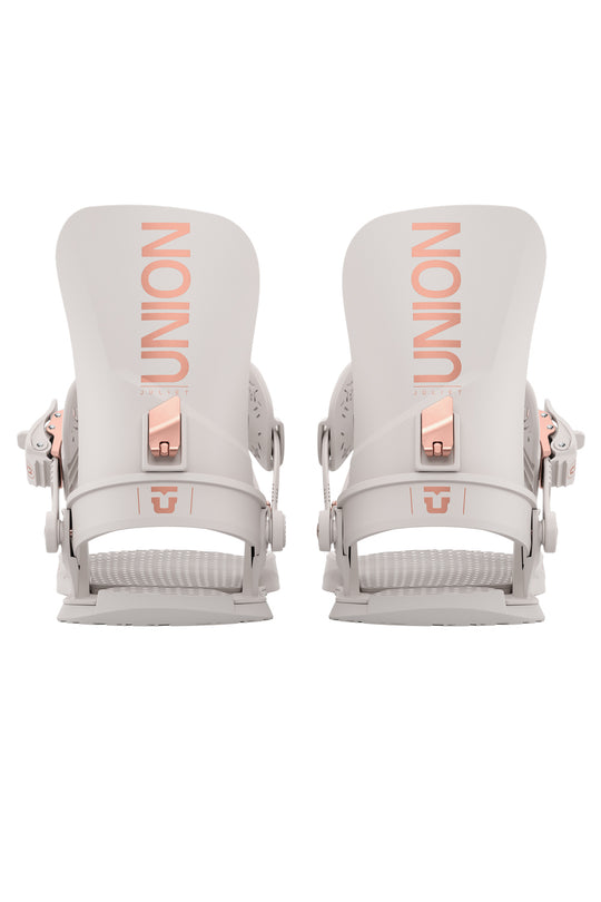 Pair of white snowboard bindings with rose gold hardware on a white background