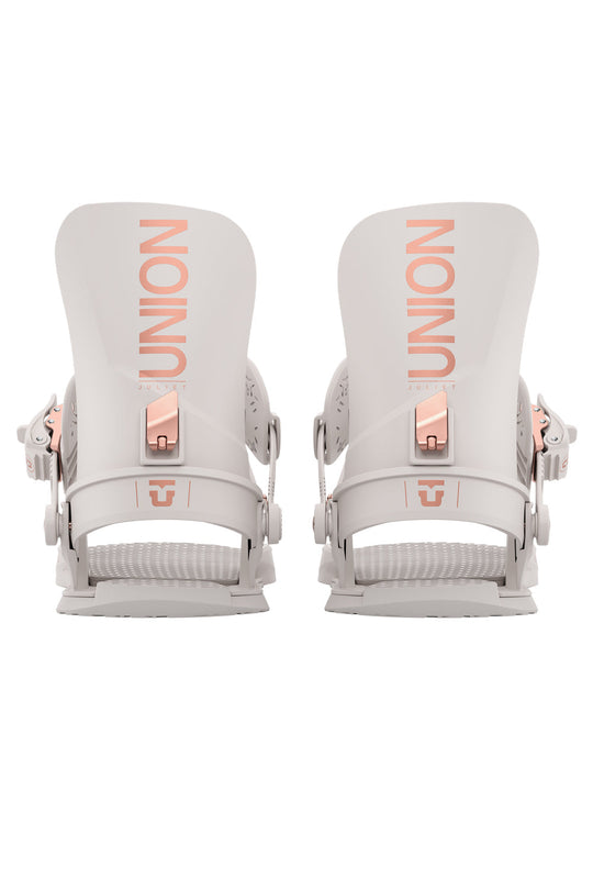 Pair of white snowboard bindings with rose gold hardware on a white background