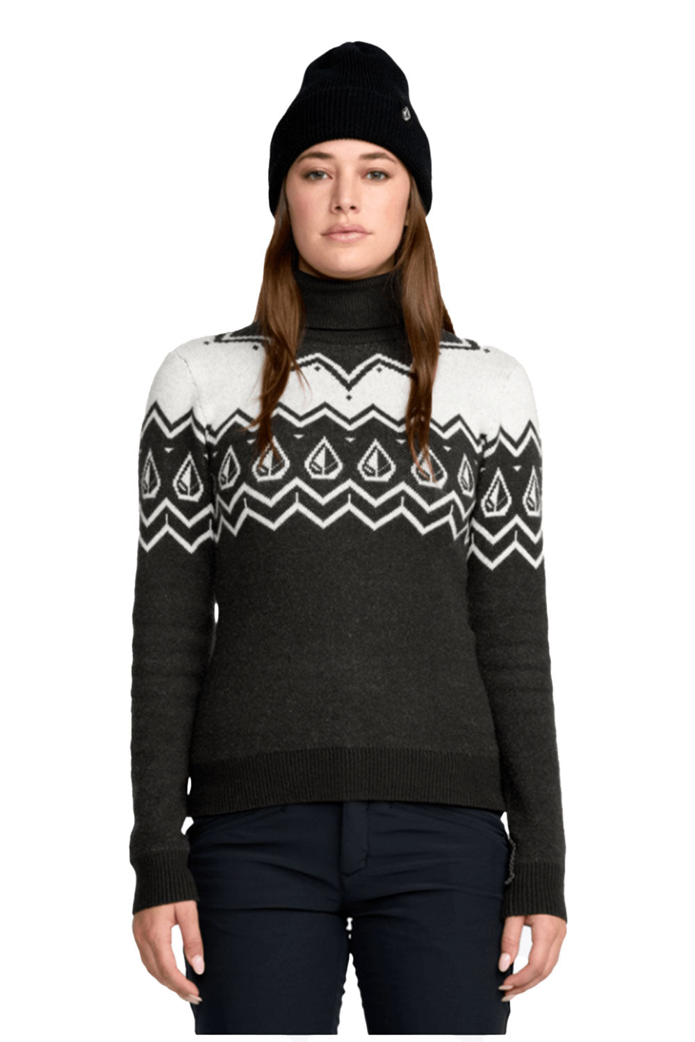 Person wearing a black sweater with white pattern, black beanie, and dark pants on a white background