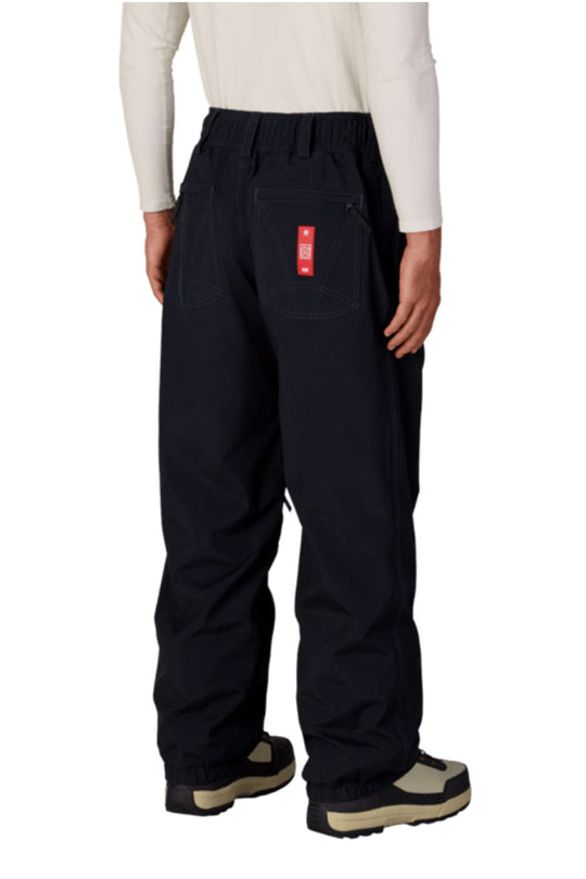 Black snow pants with a red patch on a white background