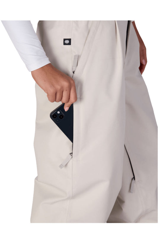 Person wearing a beige trench coat with a black phone in the pocket on a white background