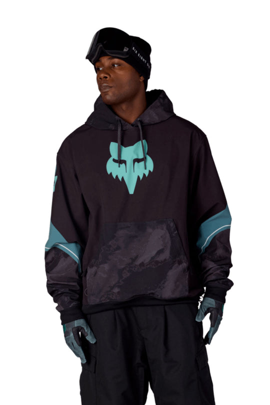 Person wearing a black and teal hoodie with a logo, standing against a white background