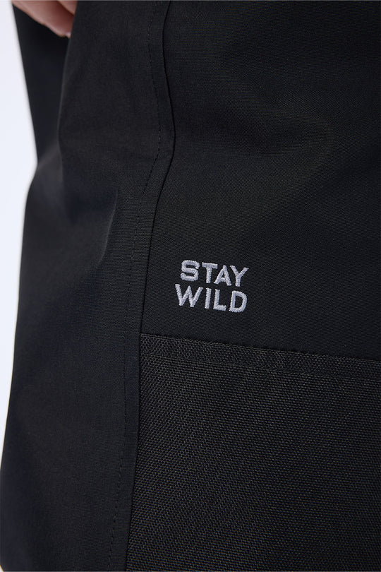 Close-up of a black garment with a small white embroidered logo reading 'STAY WILD' on the chest.