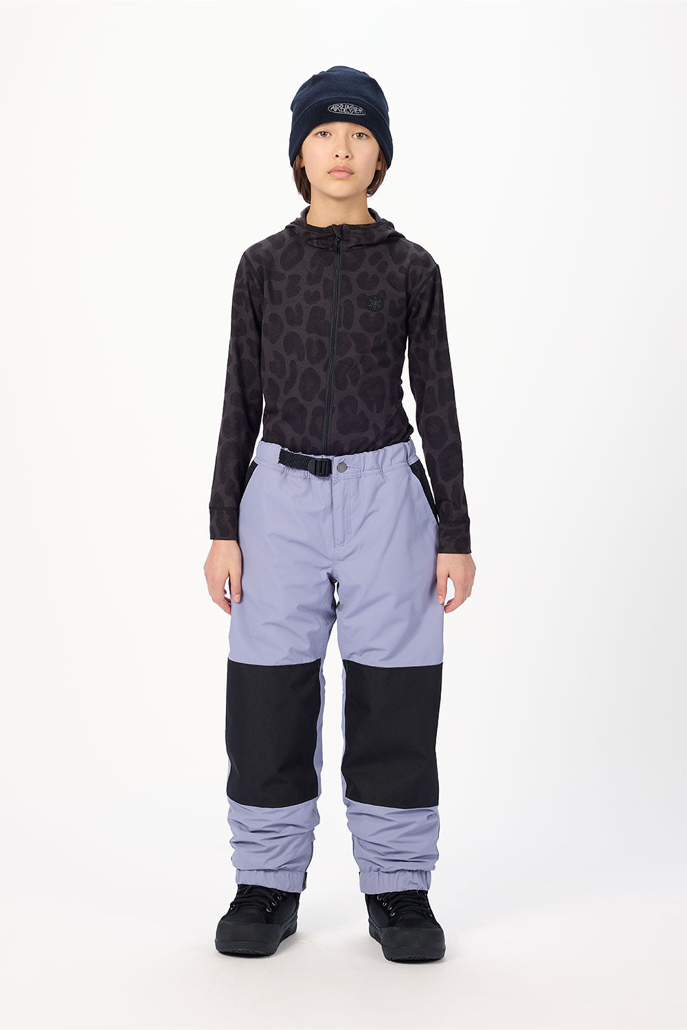 Person wearing a black patterned top and light purple pants with black accents on a white background