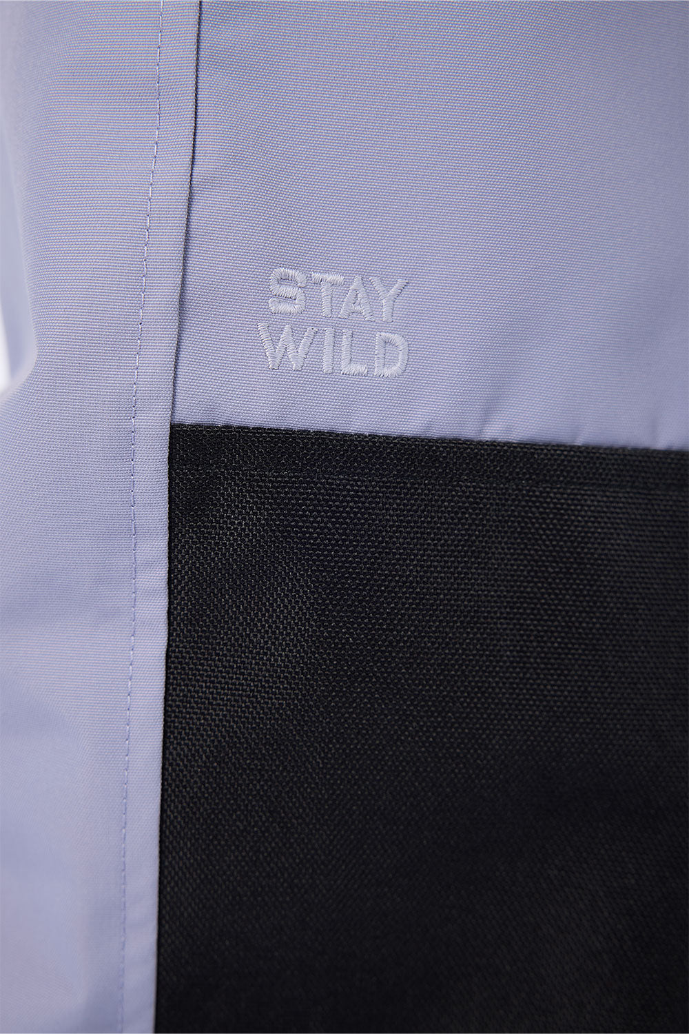 Text 'STAY WILD' on a light purple and black fabric background
