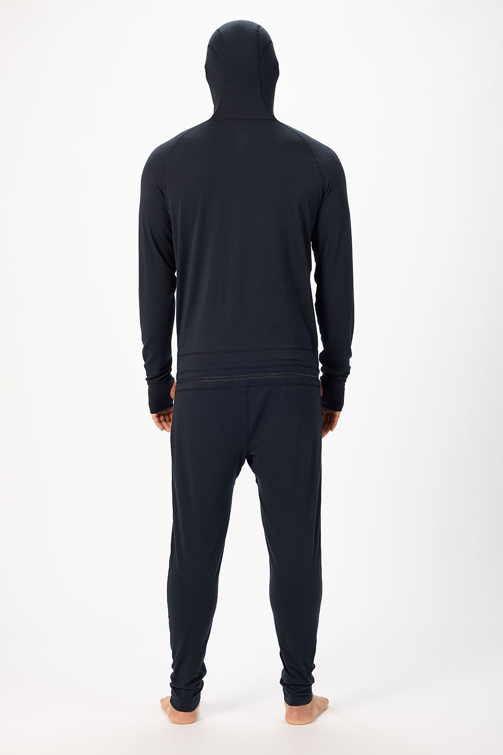 Person wearing a black hoodie and pants set on a white background