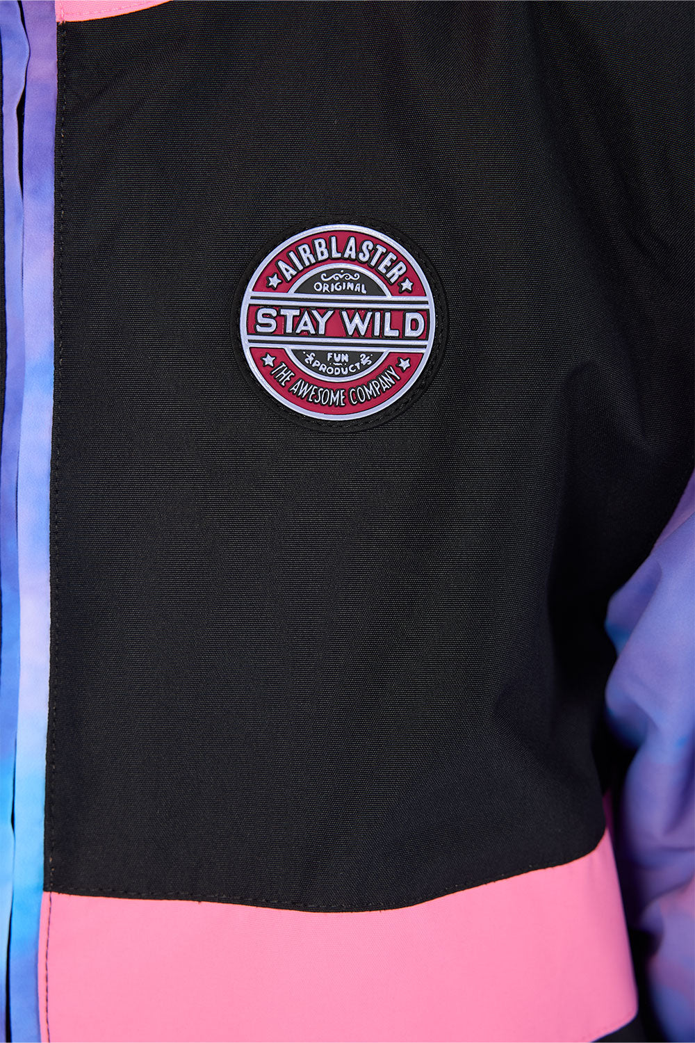 Close-up of a black jacket with a pink horizontal band and a circular embroidered patch reading 'Airblaster Stay Wild' on the chest.