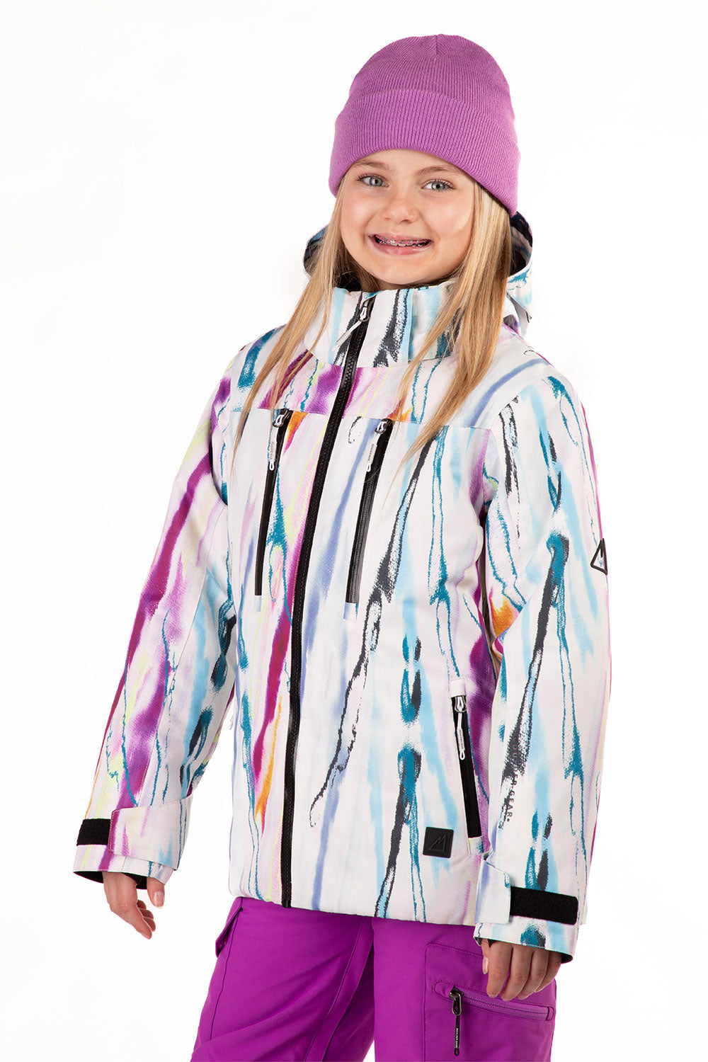 Child wearing a colorful ski jacket and purple pants on a white background