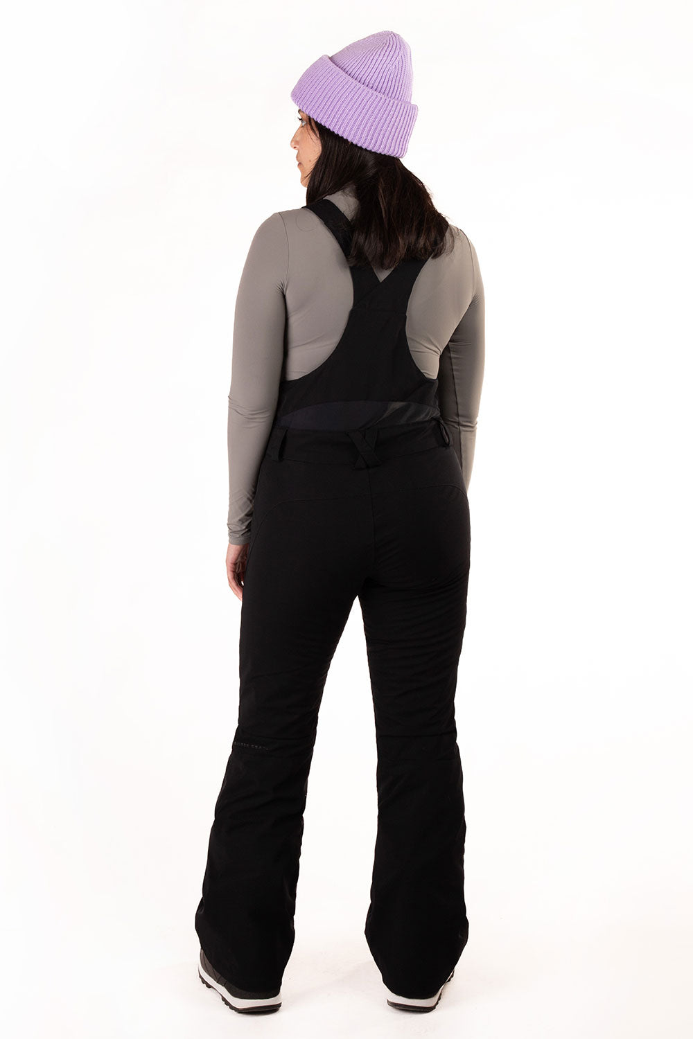 Person wearing a gray long-sleeve top and black pants with a purple beanie on a white background