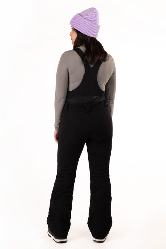Person wearing a gray long-sleeve top and black pants with a purple beanie on a white background