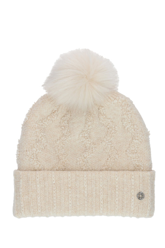A cream-colored textured knit beanie with a matching fluffy pom-pom on top and a ribbed cuff, featuring a small silver-tone logo button on the side.