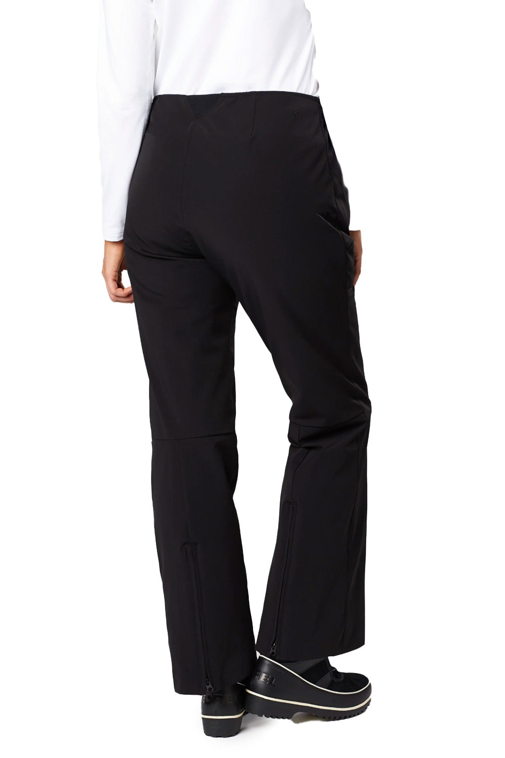 Rear view of a person wearing black wide-leg pants with side pockets, a white long-sleeve top, and black platform shoes against a plain white background.