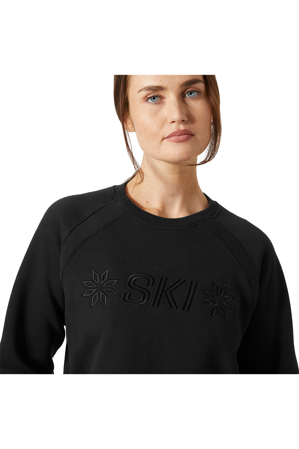 A woman wearing a black long-sleeve crewneck sweatshirt with tonal black embroidery of the word 'SKI' and snowflake-like motifs on the chest, shown against a plain white background.